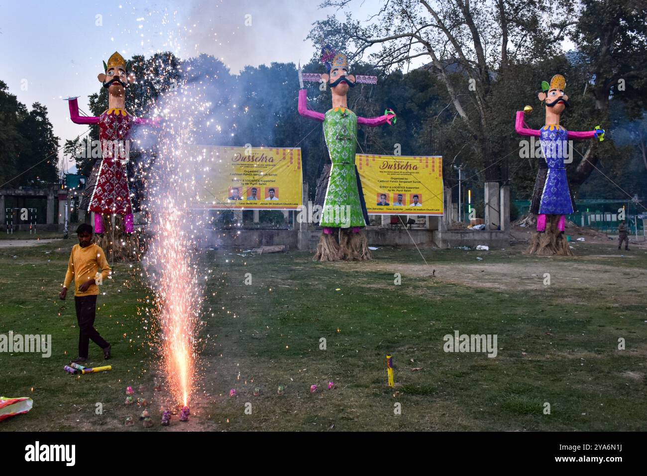 Ein hinduistischer Anhänger zündet Feuerknacker an, bevor er während des Dussehra-Festivals in Srinagar die Bilder des dämonischen Königs Ravana, seines Sohnes Meghnath und seines Bruders Kumbhkaran verbrennt. Dussehra gedenkt an den Triumph von Lord Rama über den Dämonenkönig Ravana und markiert den Sieg des Guten über das Böse. Stockfoto