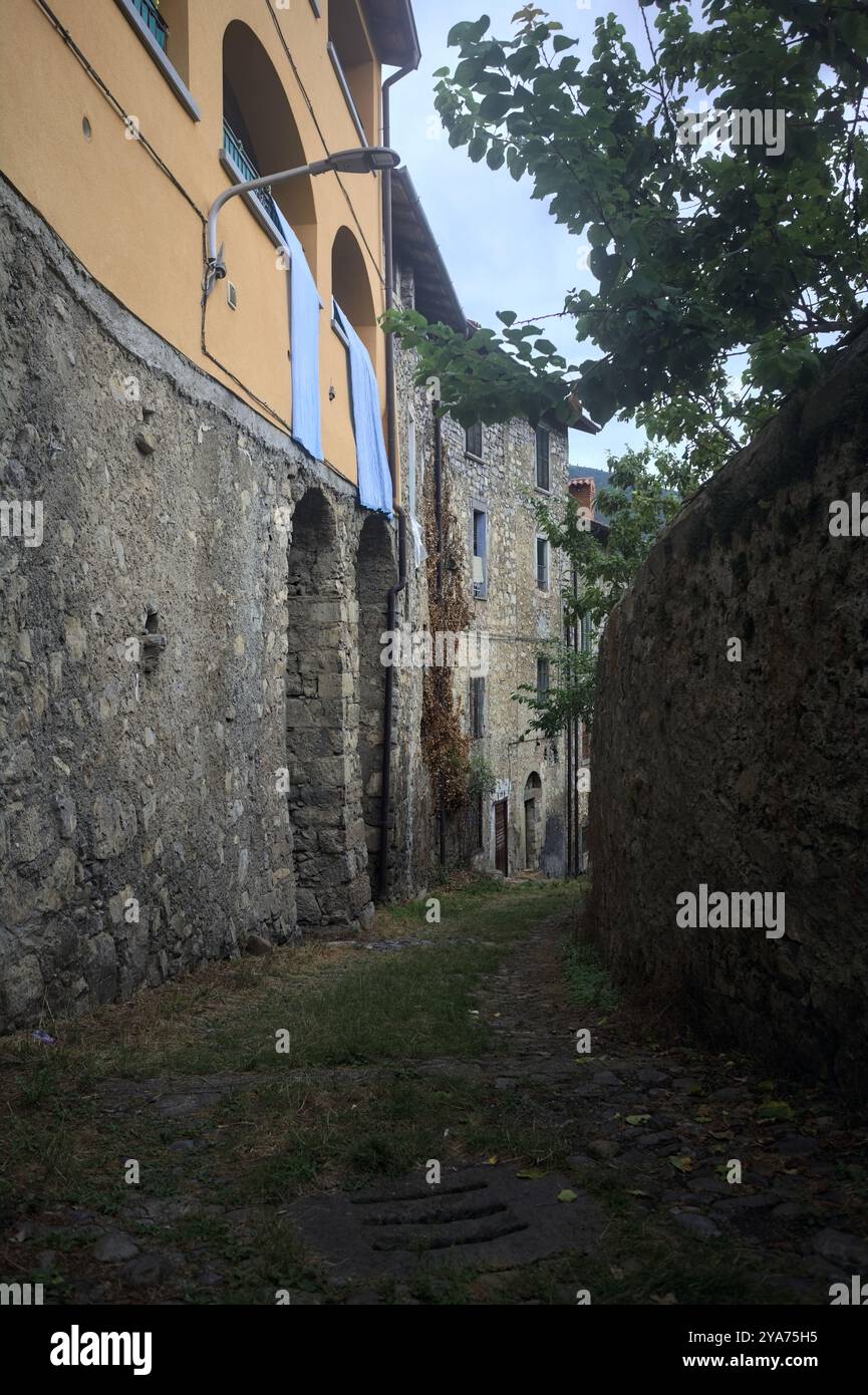 Schlampiger Kopfsteinpflasterweg zwischen einer Steinmauer und einem Steingebäude in den Bergen Stockfoto