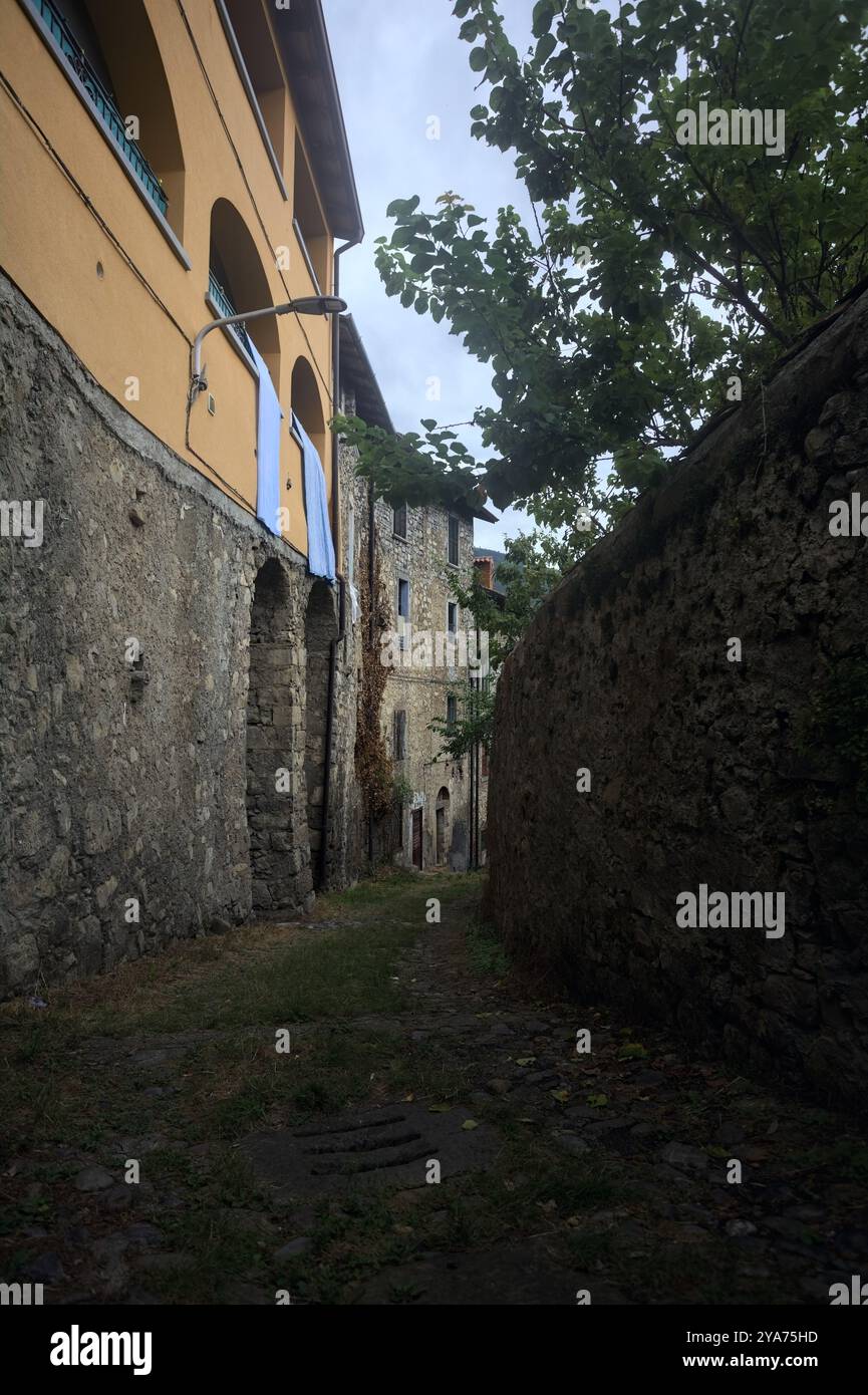 Schlampiger Kopfsteinpflasterweg zwischen einer Steinmauer und einem Steingebäude in den Bergen Stockfoto