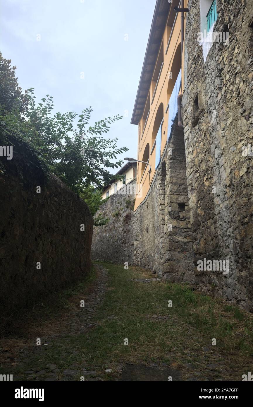 Schlampiger Kopfsteinpflasterweg zwischen einer Steinmauer und einem Steingebäude in den Bergen Stockfoto