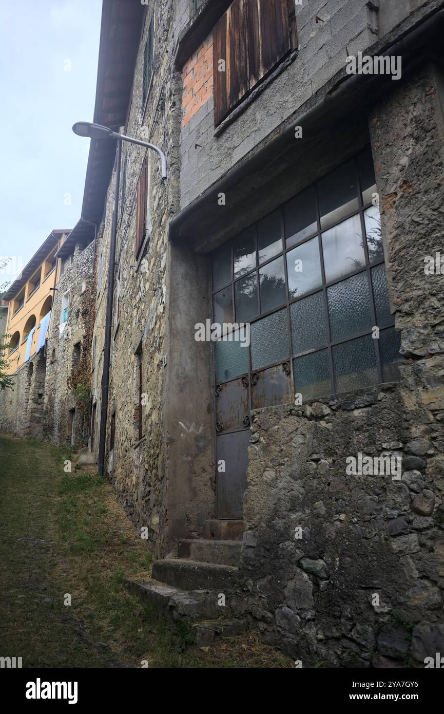 Schlampiger Kopfsteinpflasterweg zwischen einer Steinmauer und einem Steingebäude in den Bergen Stockfoto