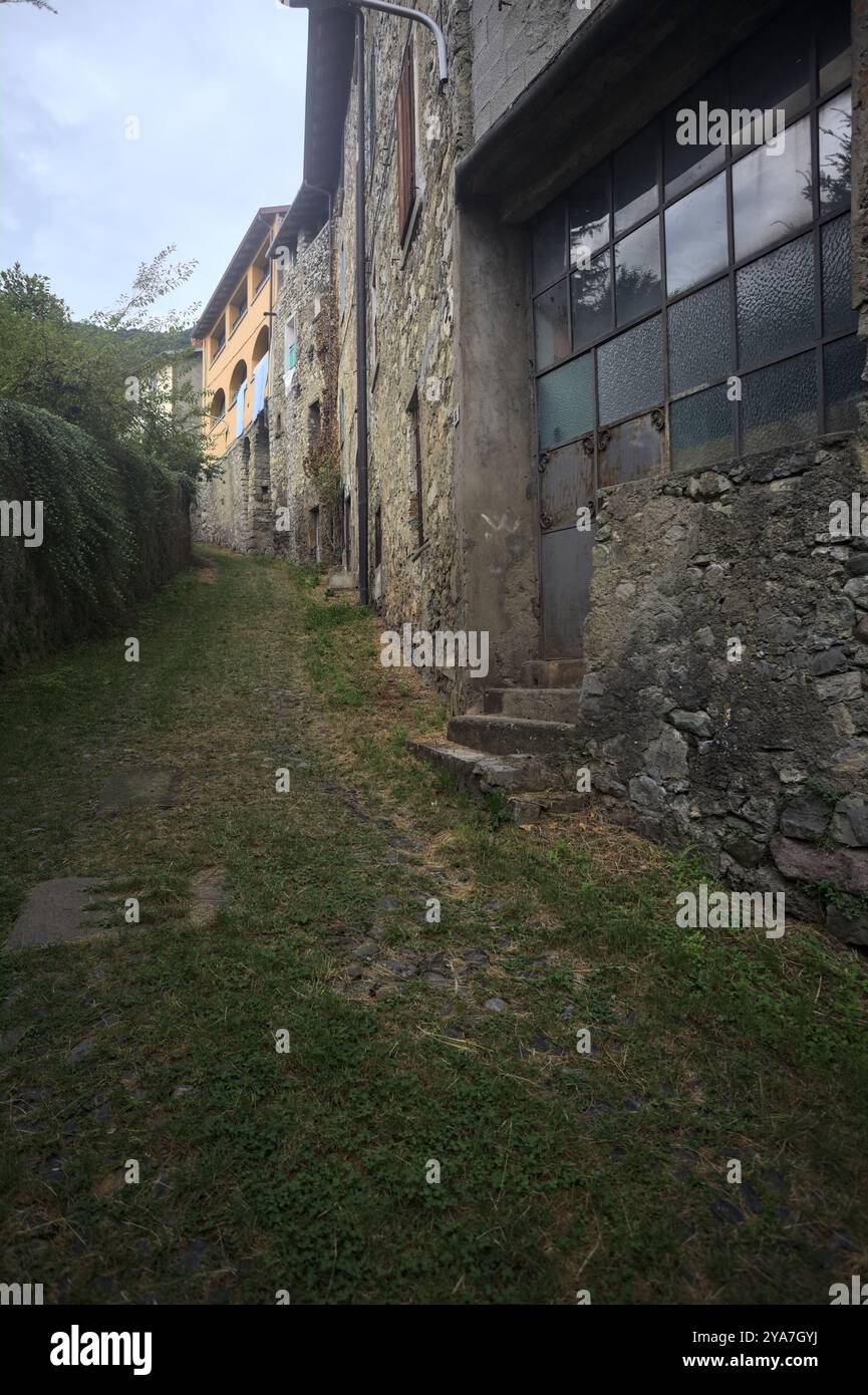 Schlampiger Kopfsteinpflasterweg zwischen einer Steinmauer und einem Steingebäude in den Bergen Stockfoto