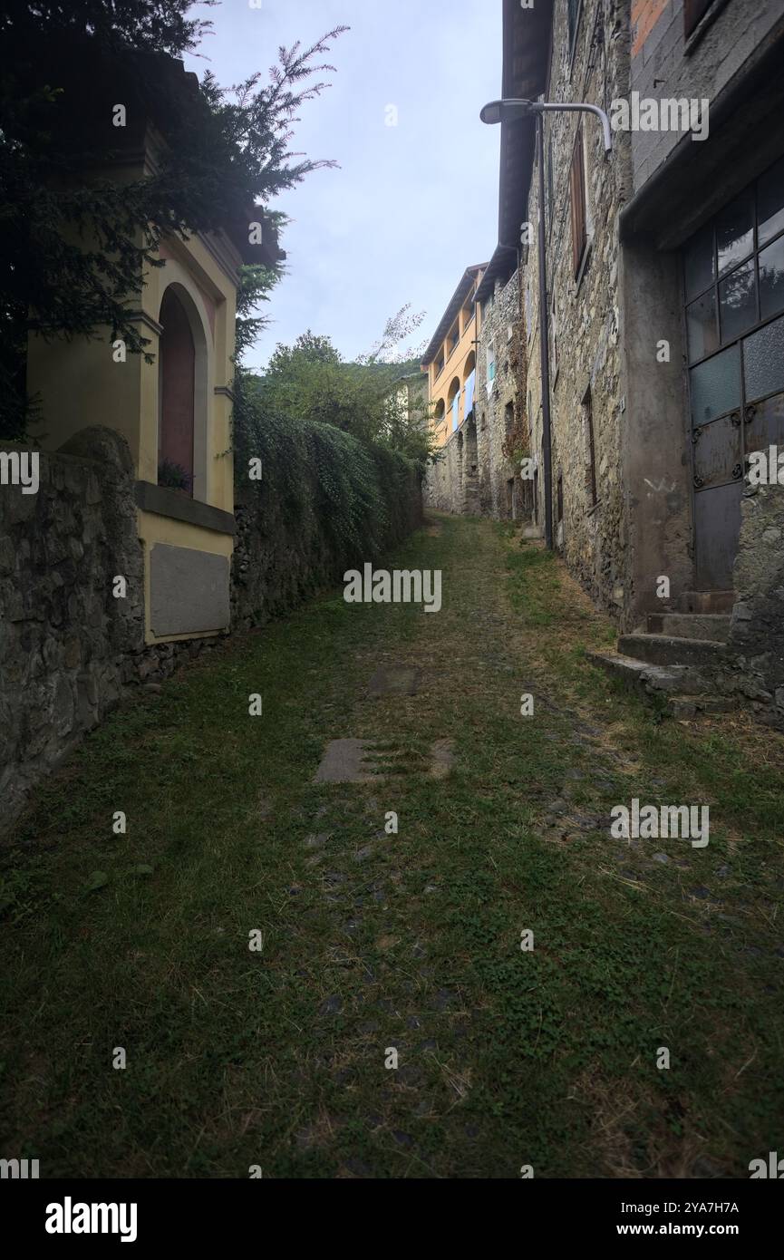 Schlampiger Kopfsteinpflasterweg zwischen einer Steinmauer und einem Steingebäude in den Bergen Stockfoto