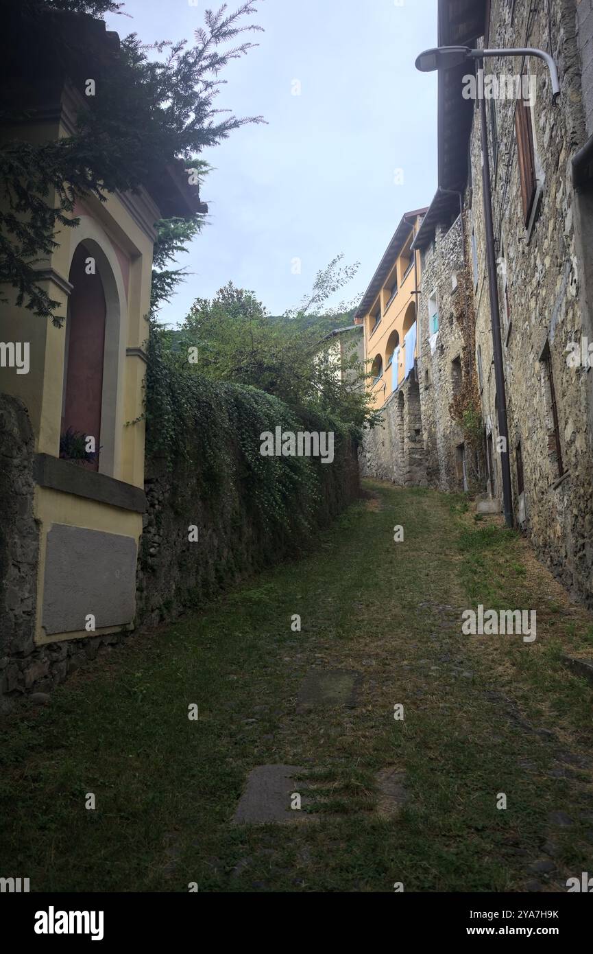 Schlampiger Kopfsteinpflasterweg zwischen einer Steinmauer und einem Steingebäude in den Bergen Stockfoto
