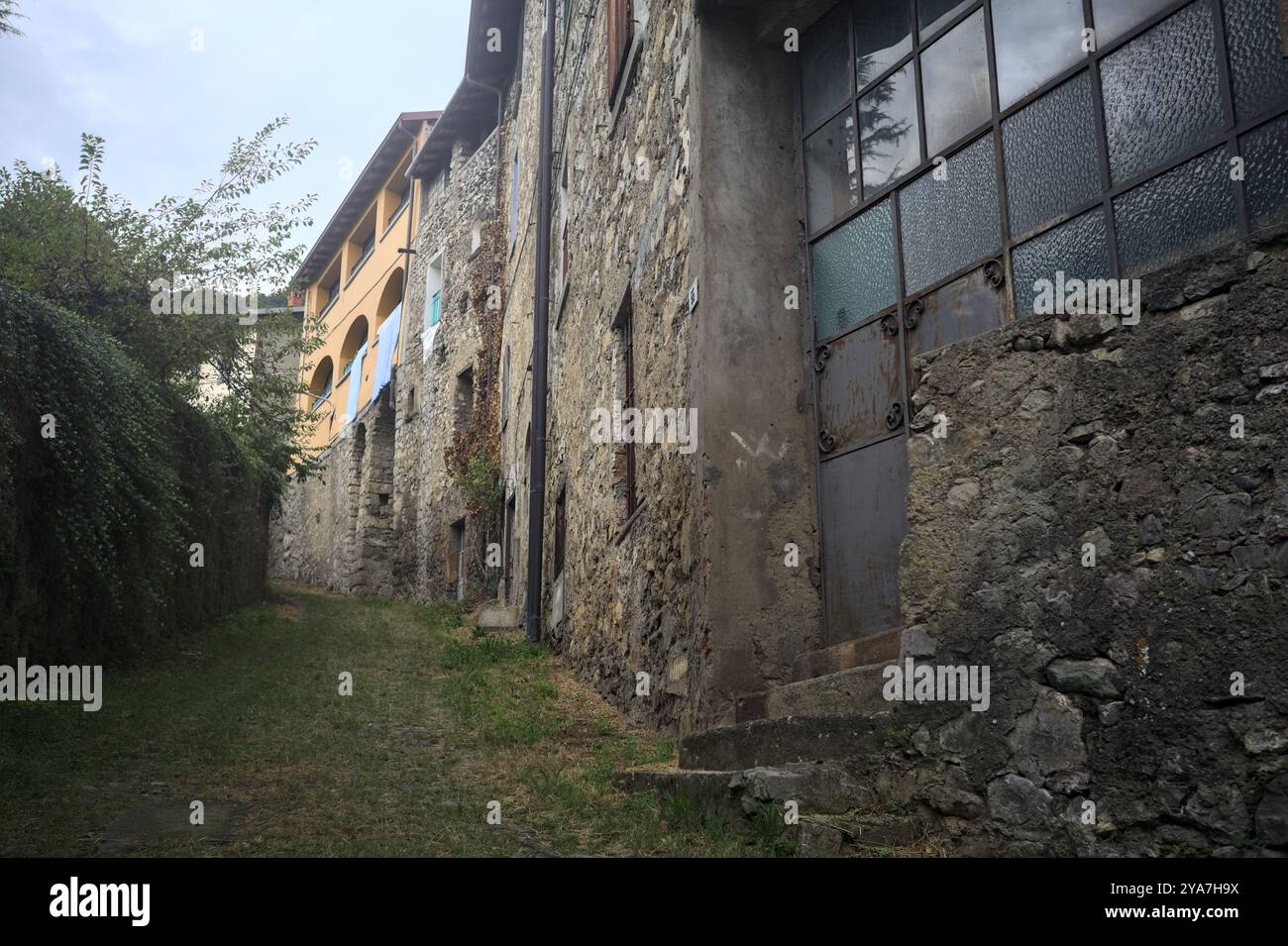 Schlampiger Kopfsteinpflasterweg zwischen einer Steinmauer und einem Steingebäude in den Bergen Stockfoto