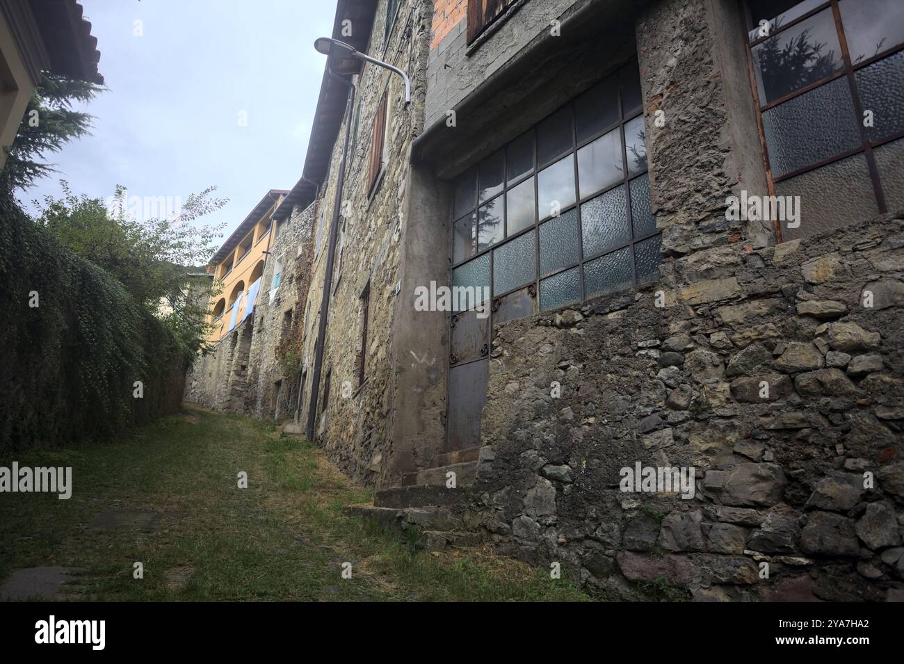 Schlampiger Kopfsteinpflasterweg zwischen einer Steinmauer und einem Steingebäude in den Bergen Stockfoto