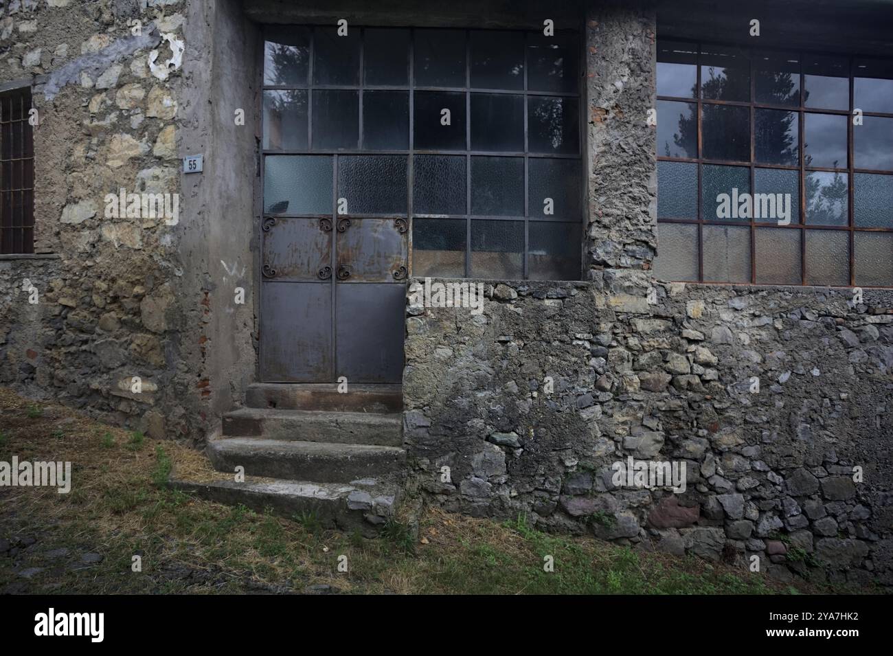 Schlampiger Kopfsteinpflasterweg zwischen einer Steinmauer und einem Steingebäude in den Bergen Stockfoto