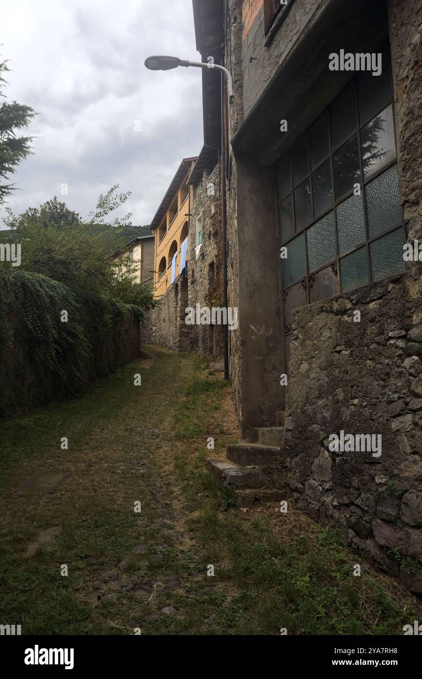 Schlampiger Kopfsteinpflasterweg zwischen einer Steinmauer und einem Steingebäude in den Bergen Stockfoto