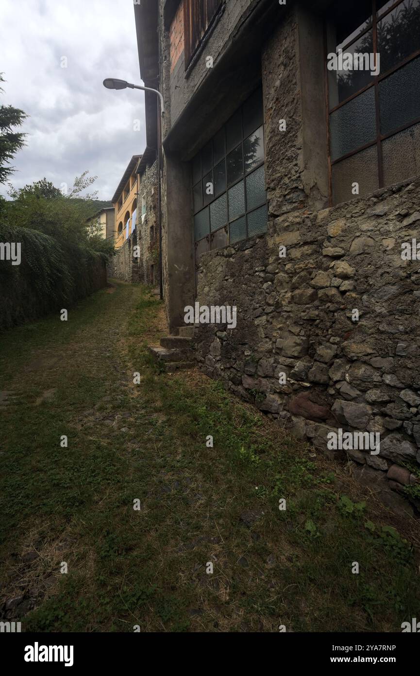 Schlampiger Kopfsteinpflasterweg zwischen einer Steinmauer und einem Steingebäude in den Bergen Stockfoto