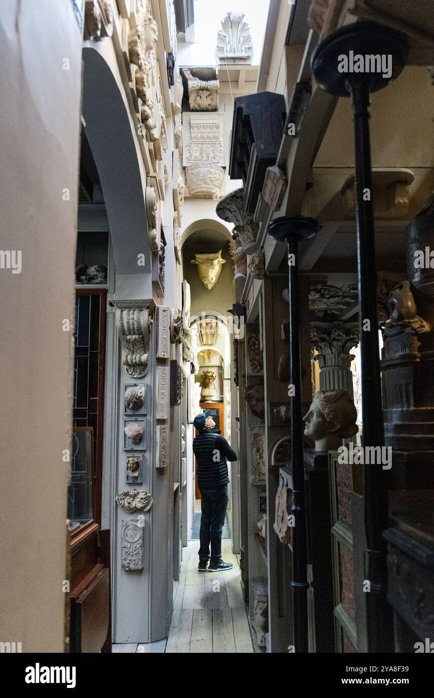 Besucher in einem engen Korridor voller Antiquitäten und Artefakte im John Soane's Museum, London, England Stockfoto