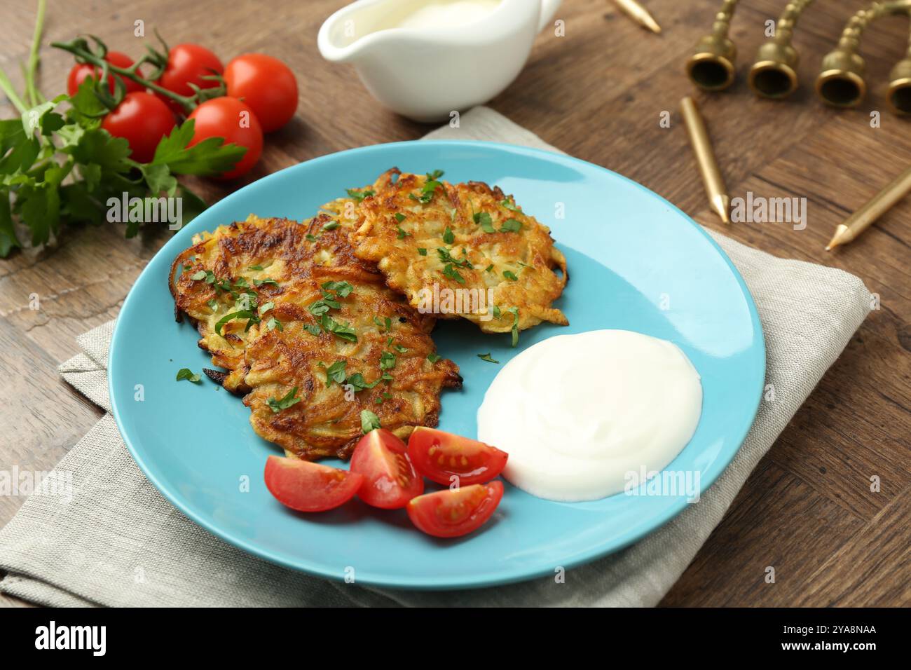 Leckere Kartoffelpfannkuchen, Menora und Kerzen auf Holztisch, Nahaufnahme. Hanukkah festliches Essen Stockfoto