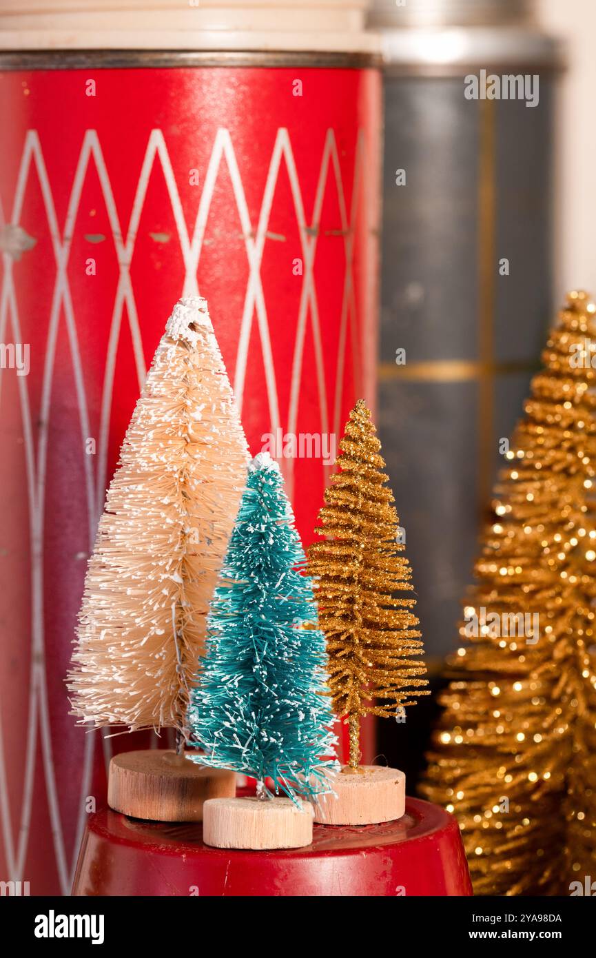 Kleine Flaschenpinsel Weihnachtsbaumdekorationen mit Vintage-roten und grauen Thermosflaschen im Hintergrund Stockfoto