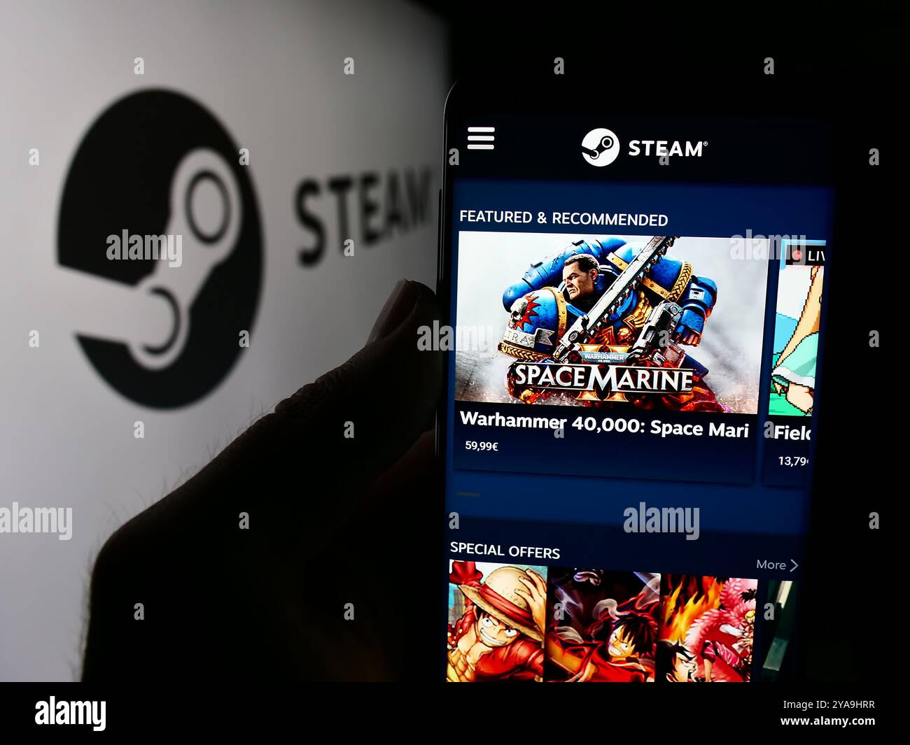 In dieser Fotoabbildung hält eine Person ein Smartphone mit der Webseite des US-amerikanischen Videospielvertriebs Steam (Valve) vor dem Logo. Stockfoto