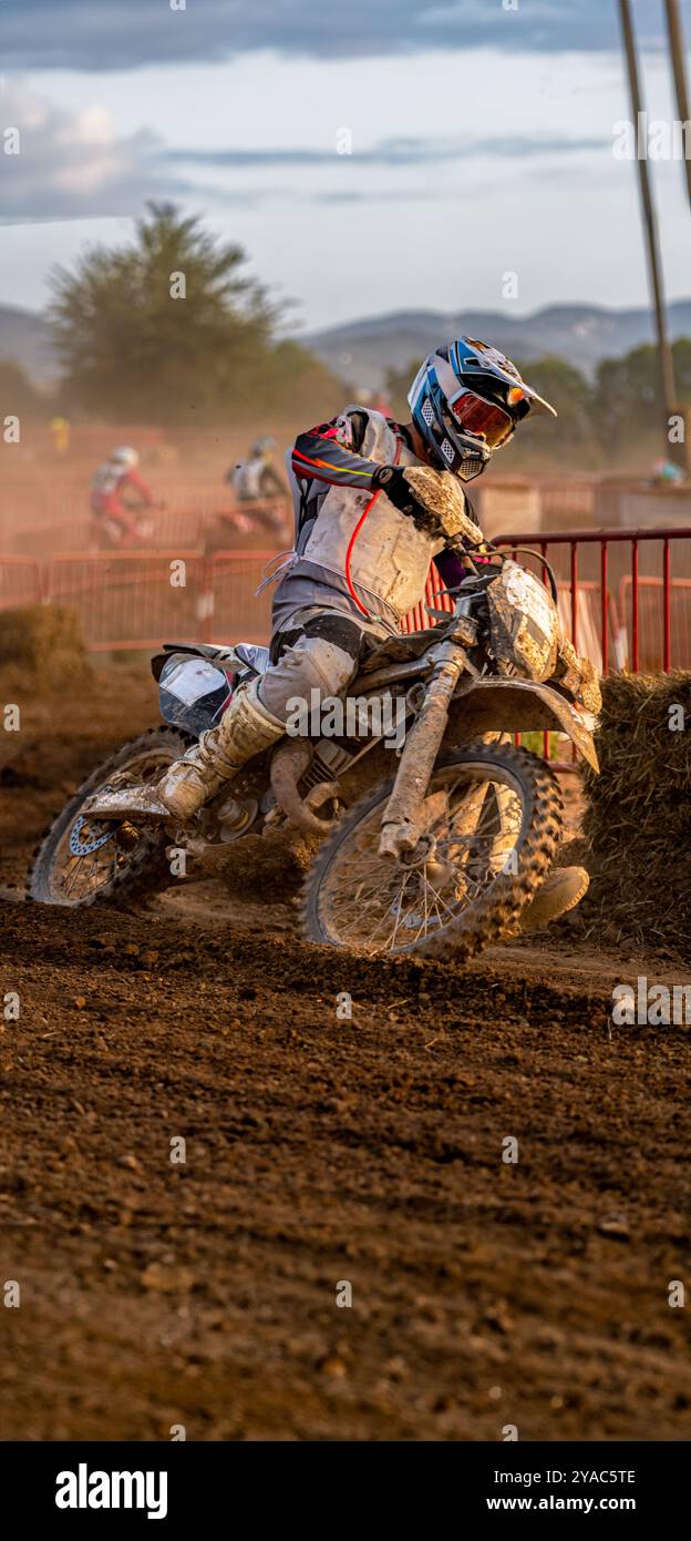 Motocross-Fahrer in Aktion dreht sein matschiges Motorrad auf nassem Gelände während eines Outdoor-Ausdauerwettbewerbs in engen Kurven. Stockfoto