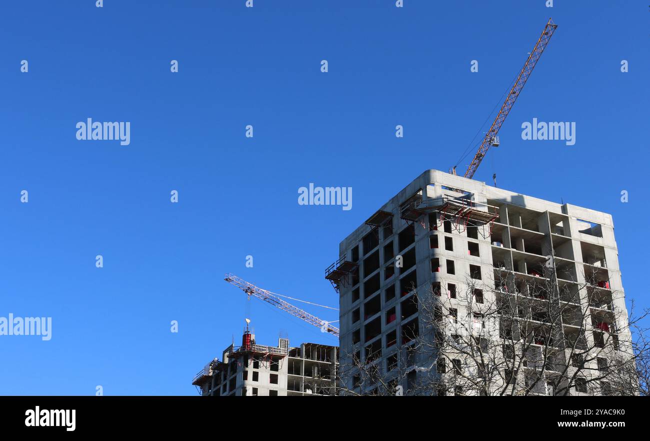 Im Bau befindliche mehrstöckige Gebäude mit Gerüsten und Baukränen oben vor blauem, klarem Himmel Stockfoto