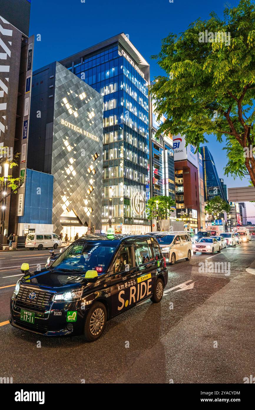 Taxis und Autos standen während der abendlichen blauen Stunde vor den Flaggschiffläden Bottega Veneta und Giorgio Armani in der Ginza. Stockfoto