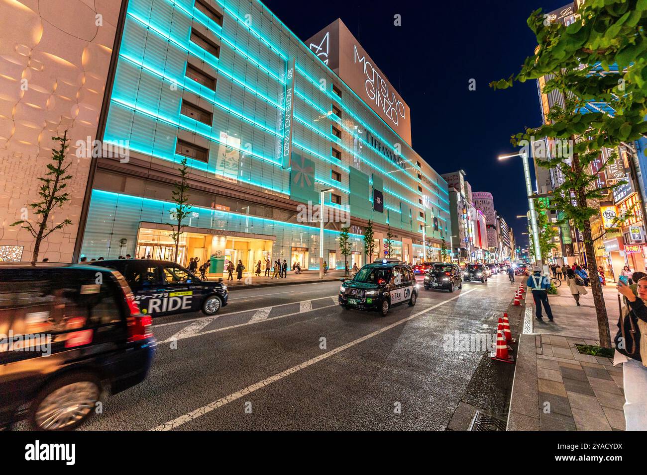 Ginza bei Nacht mit dem Wahrzeichen Matsuya Ginza und Tiffany Ladengebäude beleuchtet in blauem, grünem, diffusem Licht. Taxistände auf der Straße. Stockfoto