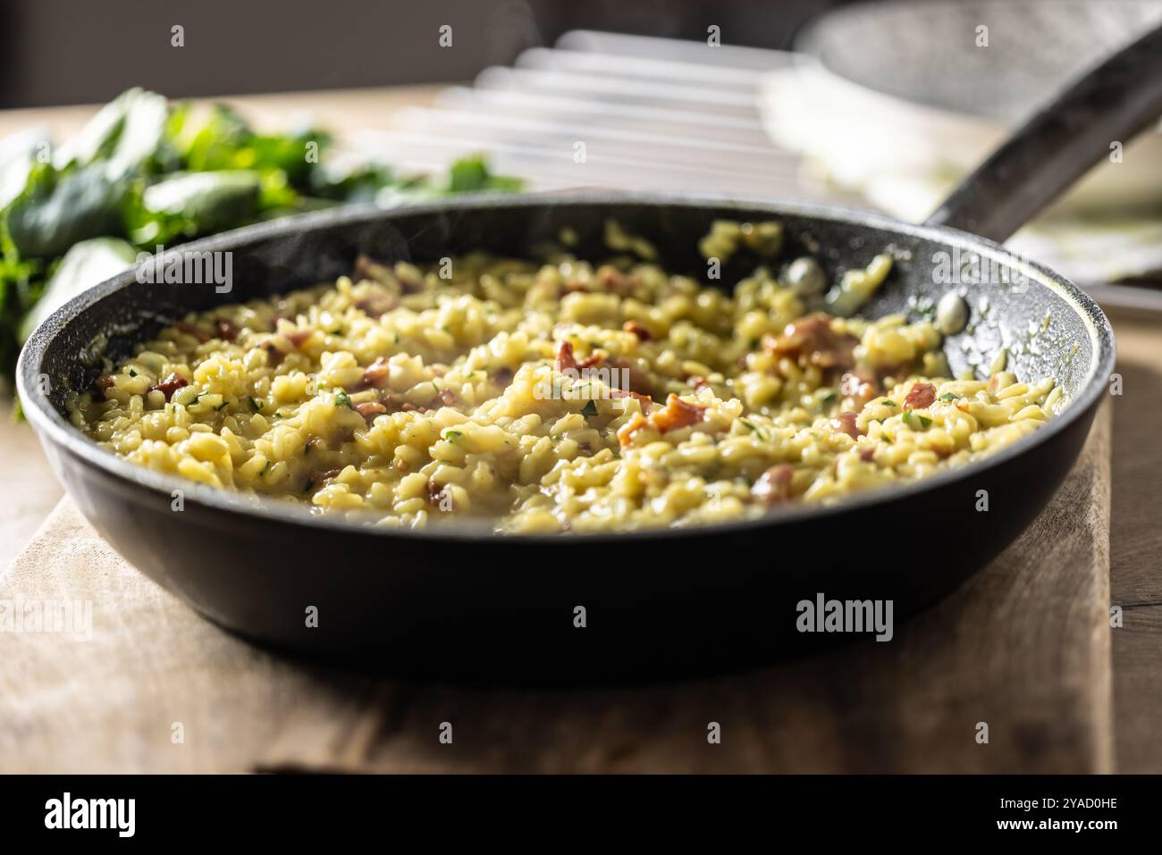 Italienisches Risotto mit Pancetta, Parmesan und Petersilie in einer Pfanne. Stockfoto