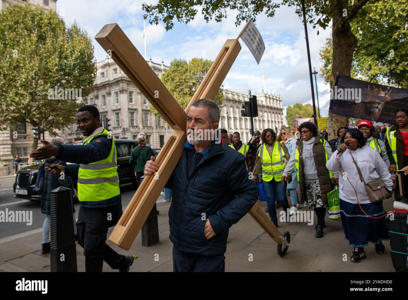 Ein Schüler Christi trägt während des marsches ein hölzernes Kreuz durch Central London. Hunderte von Christen nahmen am Marsch für Jesus Teil. Die Jünger Christi hielten dann eine Kundgebung am Trafalgar Square ab, wo sie Reden, Livemusik und Gebete hörten. Stockfoto