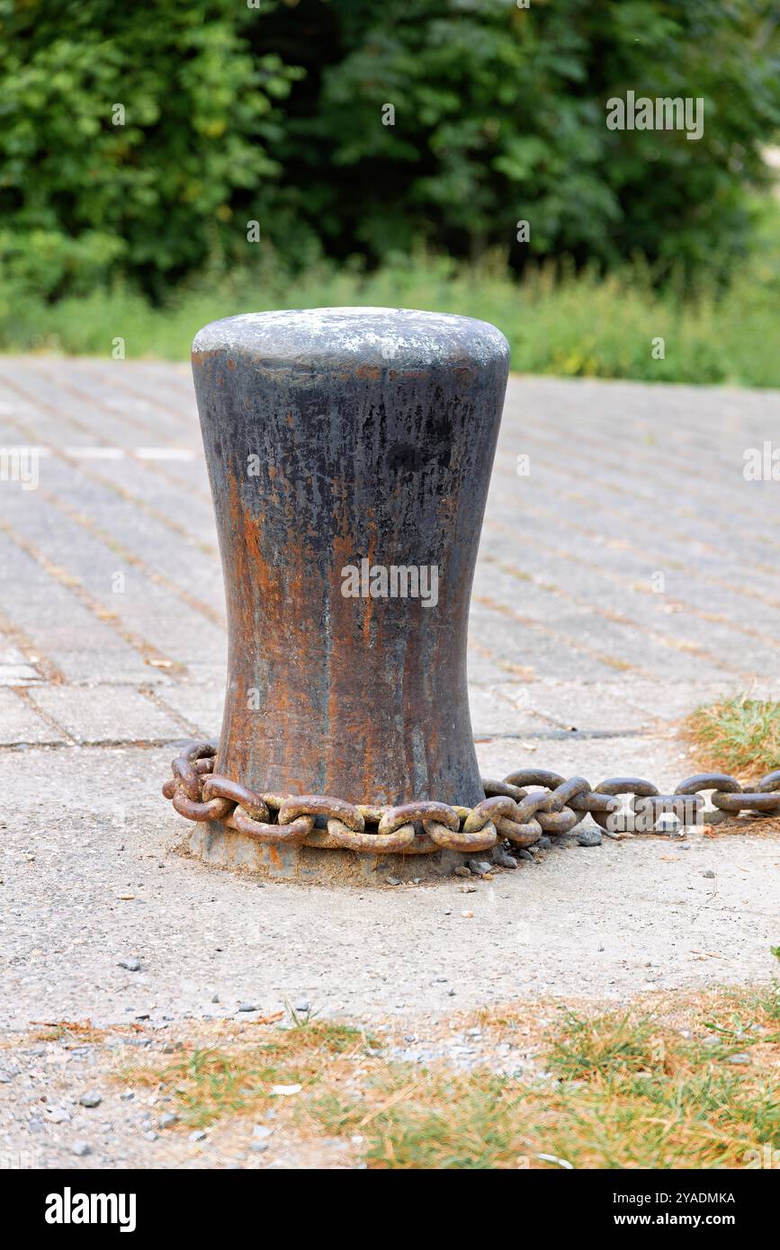 Alter rostiger Poller für Ketten und Anker, mit rostiger Kette befestigt Stockfoto