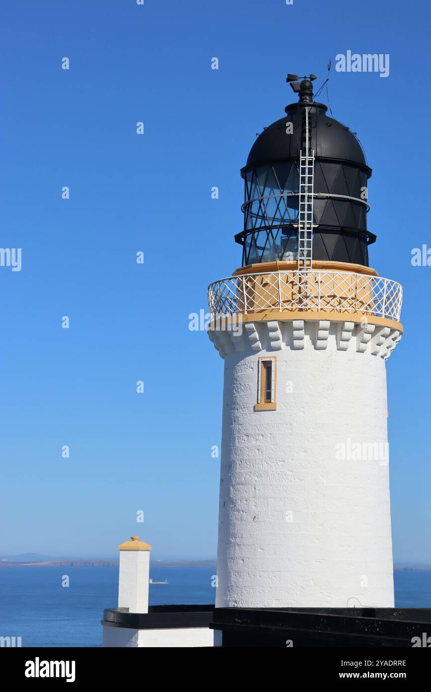 Weißer gelber und schwarzer Leuchtturm an der Nordküste schottlands am dunnet Head mit blauem Himmel Hintergrund Stockfoto