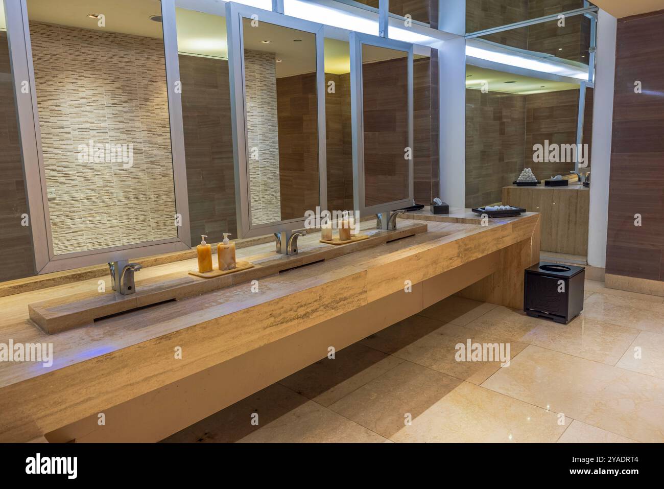 Moderne Toilette mit Marmorablageflächen, großen Spiegeln, Seifenspender und eleganten Waschbecken. Mexiko. Stockfoto