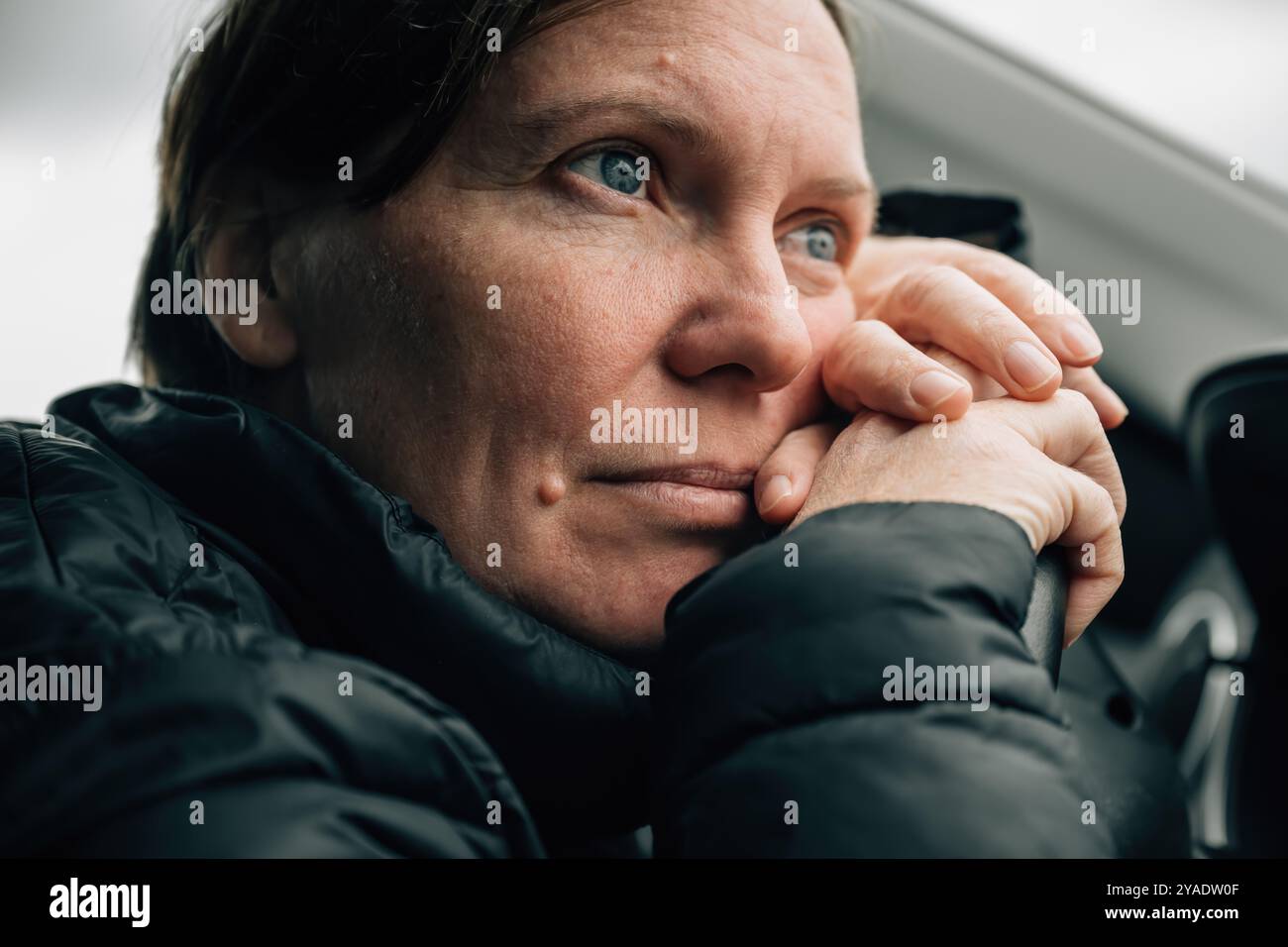 Weibliche Fahrerin, die tagträumt und denkt, während sie ihren Kopf während des Staus im Herbst gegen das Lenkrad eines Autos lehnt, selektiv fokussiert Stockfoto