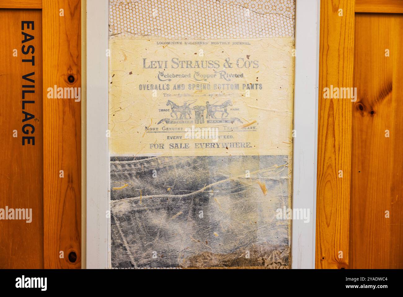 Nahaufnahme des Vintage-Brandings von Levi Strauss Co. An der Wand des Ankleideraums in Levi's Boutique, neben einer Holztür mit der Aufschrift East Village. Neu. York. USA. Stockfoto