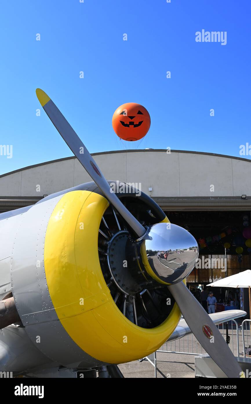 IRVINE, KALIFORNIEN - 5. OKT 2024: Antikes Flugzeug im Great Park mit Ballonfahrt mit Kürbisgesicht, das über dem Hangar ragt. Stockfoto