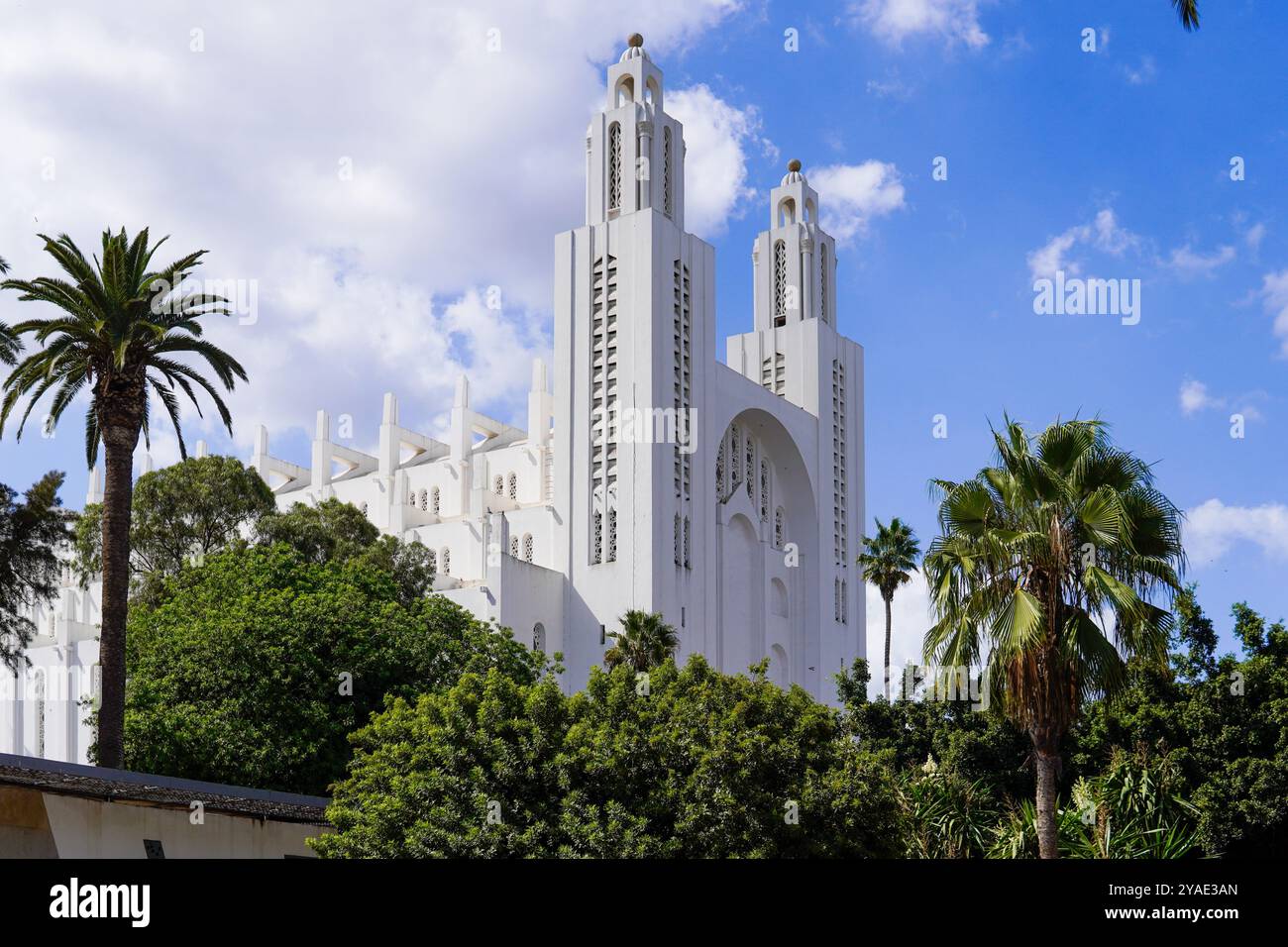 Eine wunderschöne weiße Kathedrale mit komplizierten architektonischen Details, vor einem teilweise bewölkten blauen Himmel und umgeben von üppigen grünen Palmen Stockfoto