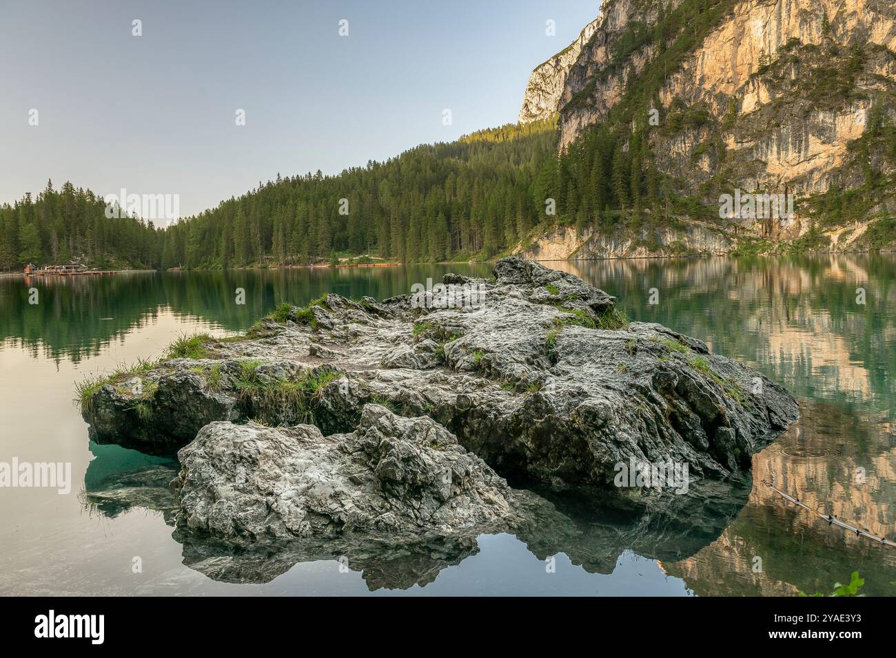 Zerklüftete Felsen spiegeln sich im smaragdgrünen Wasser des Pragser Wildsees, mit Alpenwäldern und Kalkfelsen in den Dolomiten, Südtirol Stockfoto