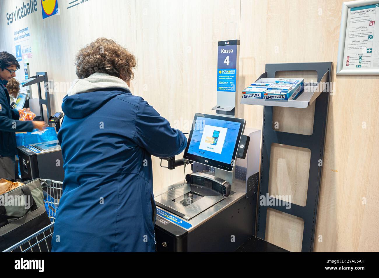 Die Frau scannt Produkte und zahlt dann elektronisch an einer Selbstkasse. In einem Supermarkt. Stockfoto