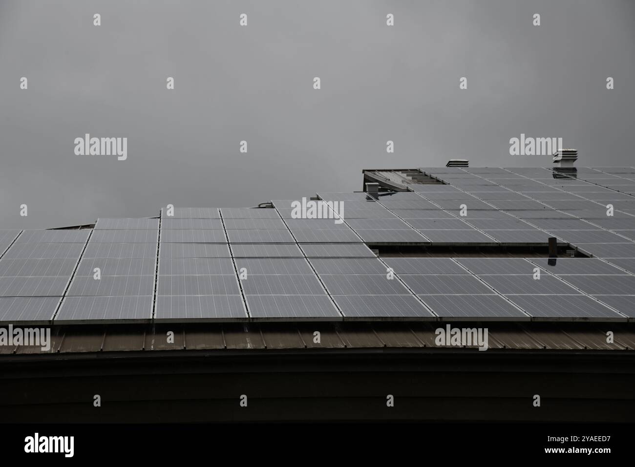 Dunkles Dach mit Sonnenkollektoren an regnerischen Tagen, die abstraktes Design und Muster bilden Stockfoto