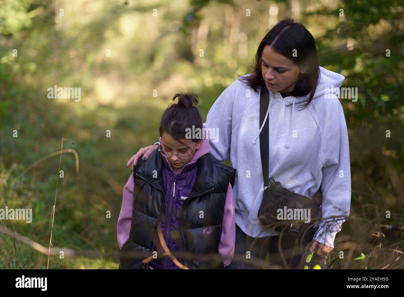 Mutter umarmt ihre kleine Tochter auf einem Spaziergang im Herbstwald. Happy Family Life Konzept Stockfoto