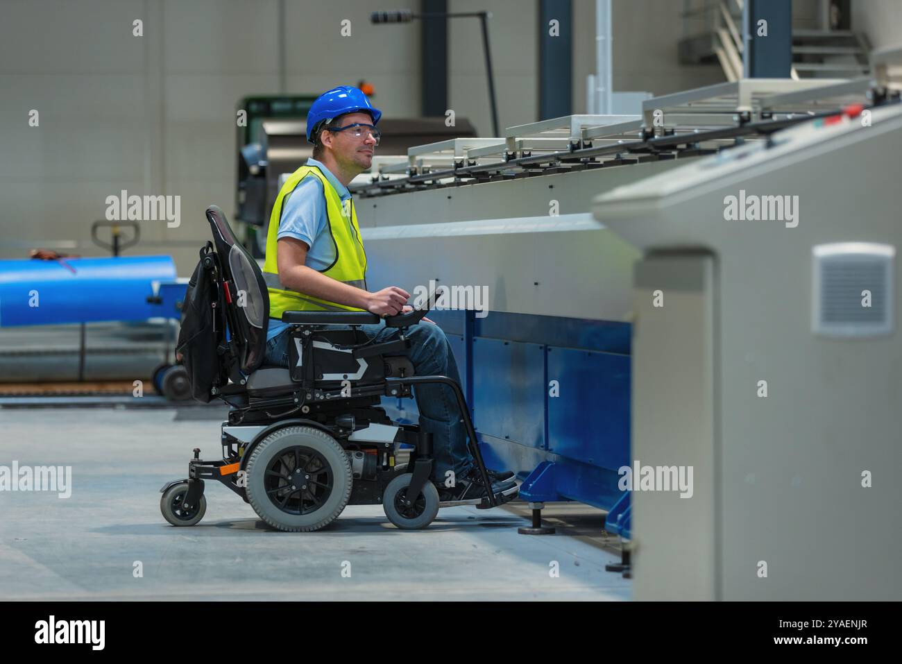 Fertigungsingenieur mit Behinderung in einer Fabrik mit gelber Weste und blauem Helm bei der Arbeit. Stockfoto