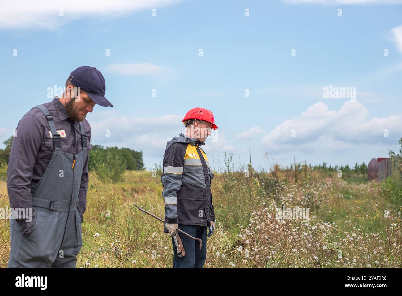 Arbeiter in Overalls im Freien in ländlichen Gebieten. Arbeitsberufe. Wasserversorgungsspezialisten. Stockfoto Arbeiter in Overalls im Freien in ländlichen Gebieten. Arbeitsberufe. Wasserversorgungsspezialisten. Stockfoto