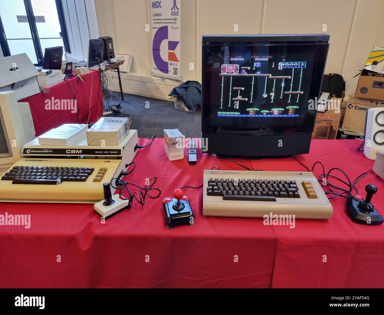 Alte, historische Commodore-Computer mit Monitoren auf einem roten Tisch im HCC Kennisdag in der Expo Houten, Niederlande Stockfoto