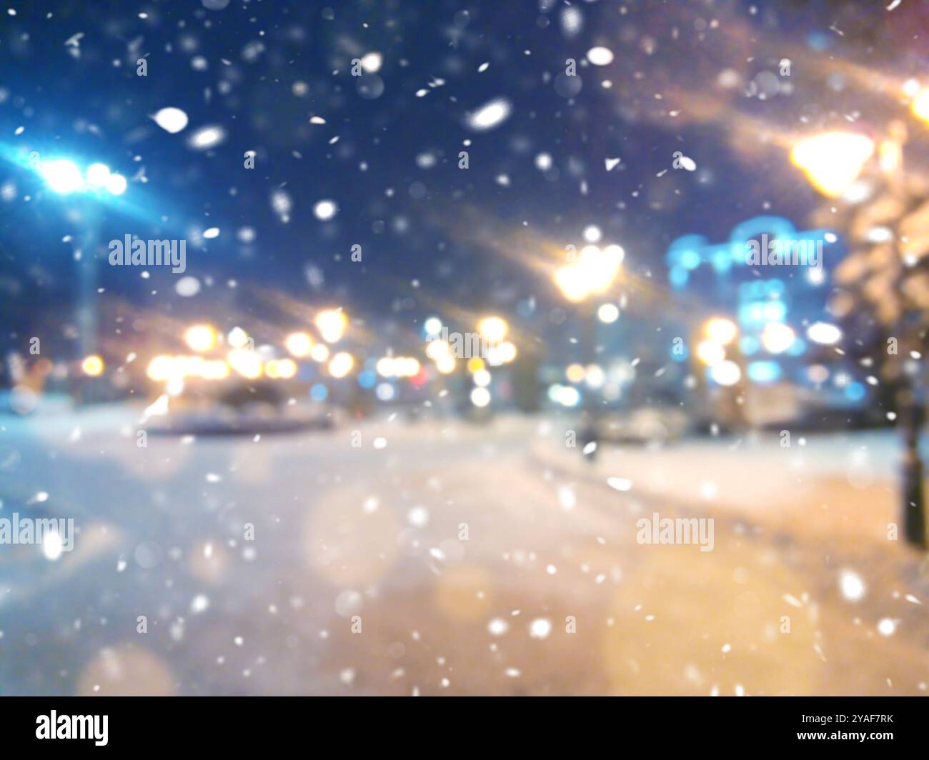 Unscharfer Hintergrund. Stadtblick, Lichter, fallender Schnee, Nacht, Straße, Bokeh-Spots von Scheinwerfern Autos. Urbane Kulisse Winterlandschaft der Straße in der Stadt AT Stockfoto