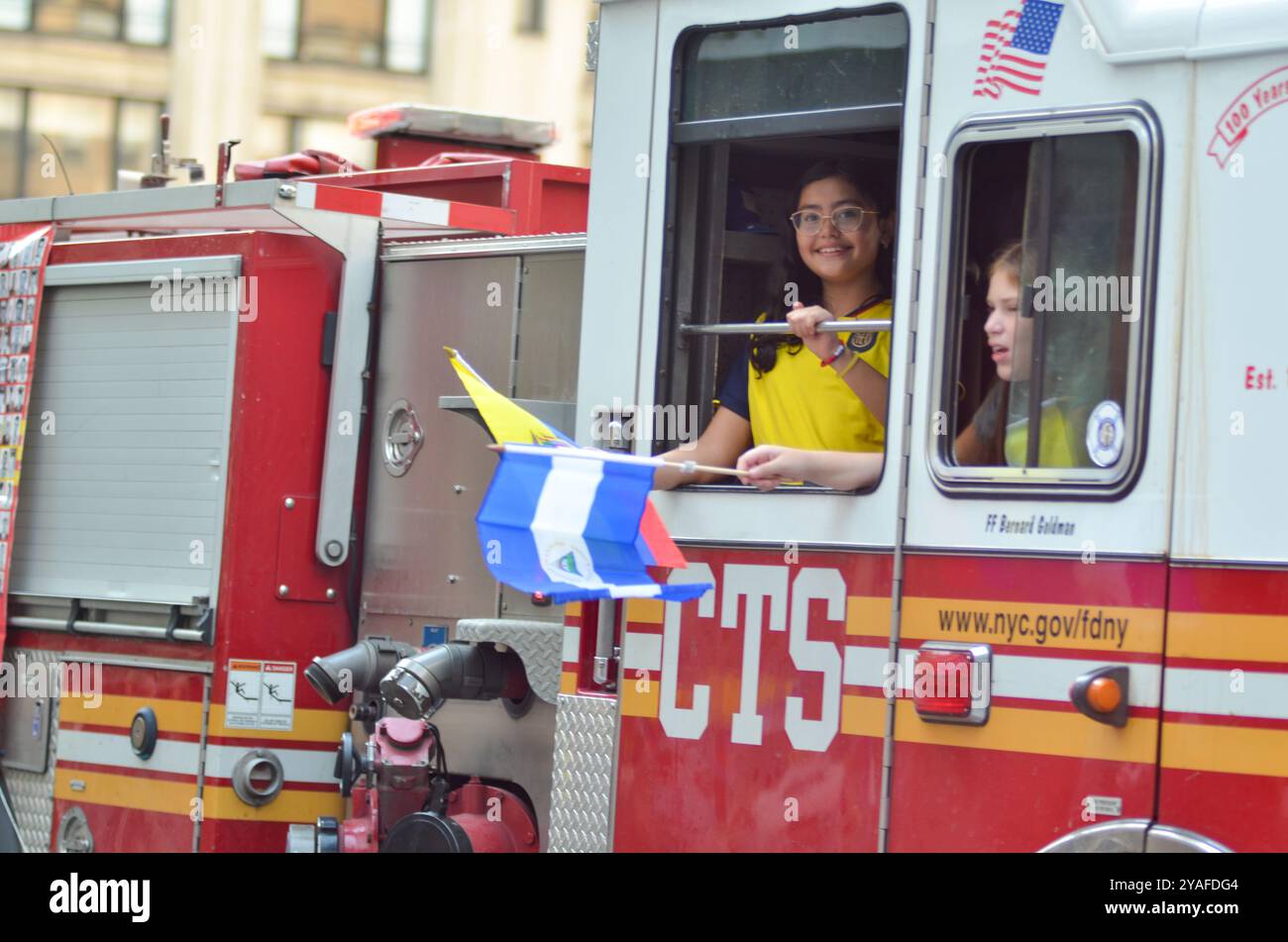 New York, New York, USA. Oktober 2024. Junge Teilnehmer, die Flaggen von einem FDNY-Feuerwehrwagen schwenken, bei der Hispanic Day Parade entlang der Sixth Avenue in New York City. (Kreditbild: © Ryan Rahman/Pacific Press via ZUMA Press Wire) NUR REDAKTIONELLE VERWENDUNG! Nicht für kommerzielle ZWECKE! Quelle: ZUMA Press, Inc./Alamy Live News Stockfoto