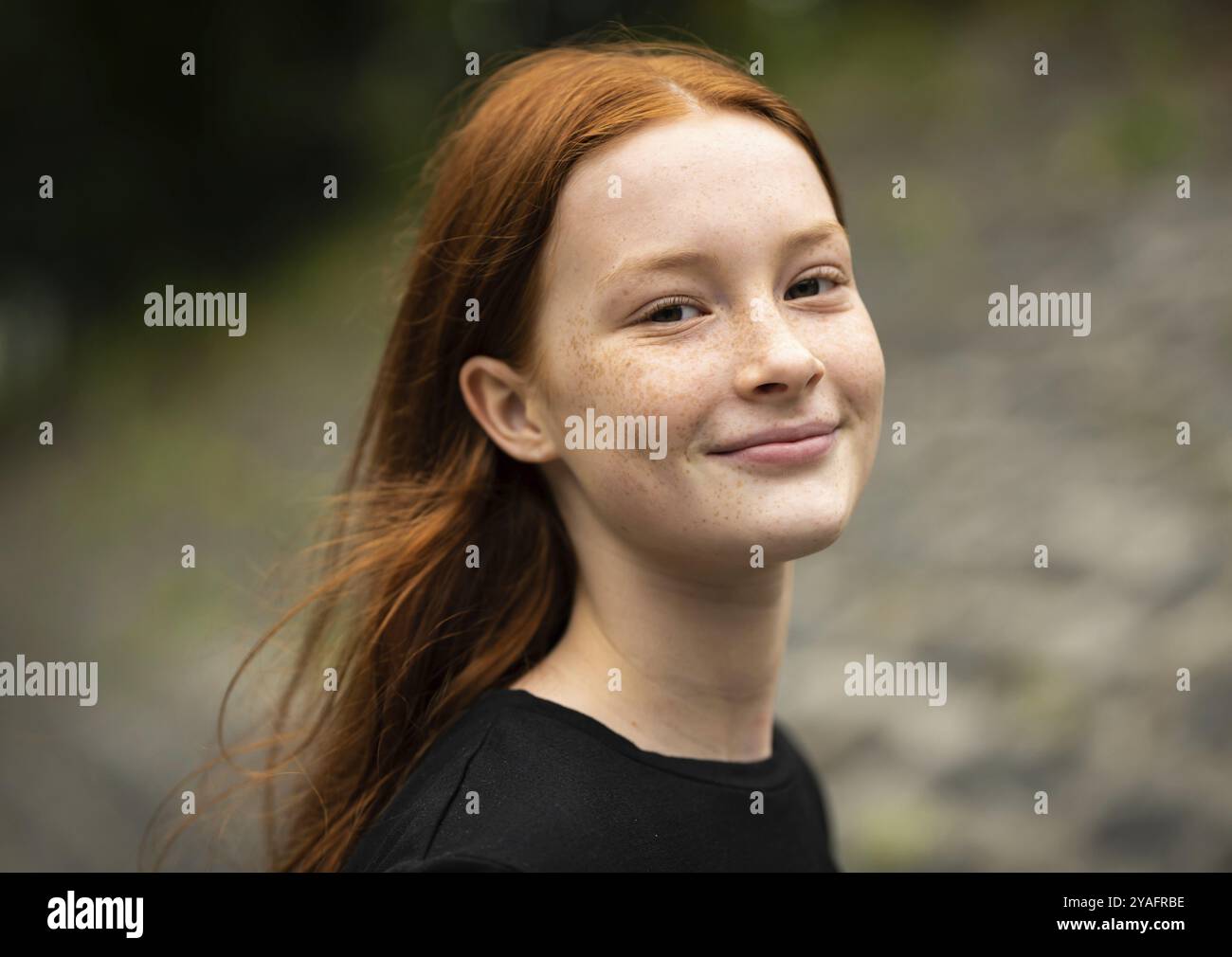 Rothaariges zwölfjähriges Mädchen mit Sommersprossen posiert mit Natur-Bokeh-Hintergrund, Jette, Belgien, Europa Stockfoto