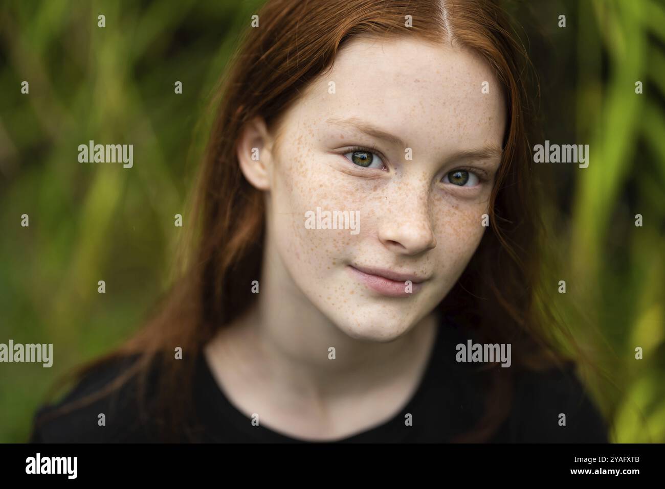 Rothaarige zwölf Jahre altes Mädchen mit Sommersprossen posiert mit Ein Natur Bokeh Hintergrund Stockfoto