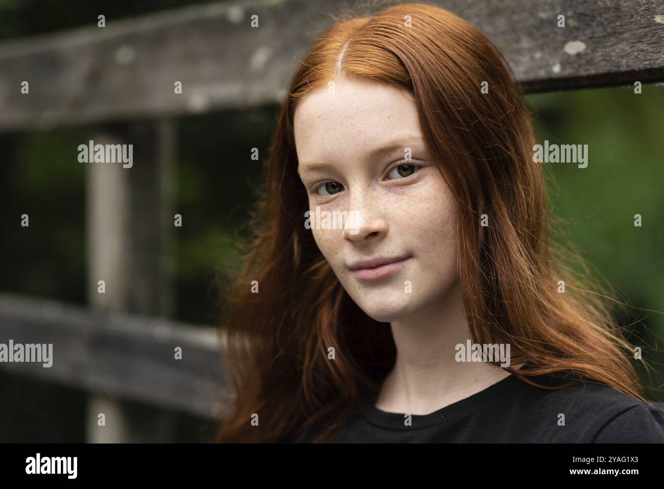 Rothaarige zwölf Jahre altes Mädchen mit Sommersprossen posiert mit Ein Natur Bokeh Hintergrund Stockfoto