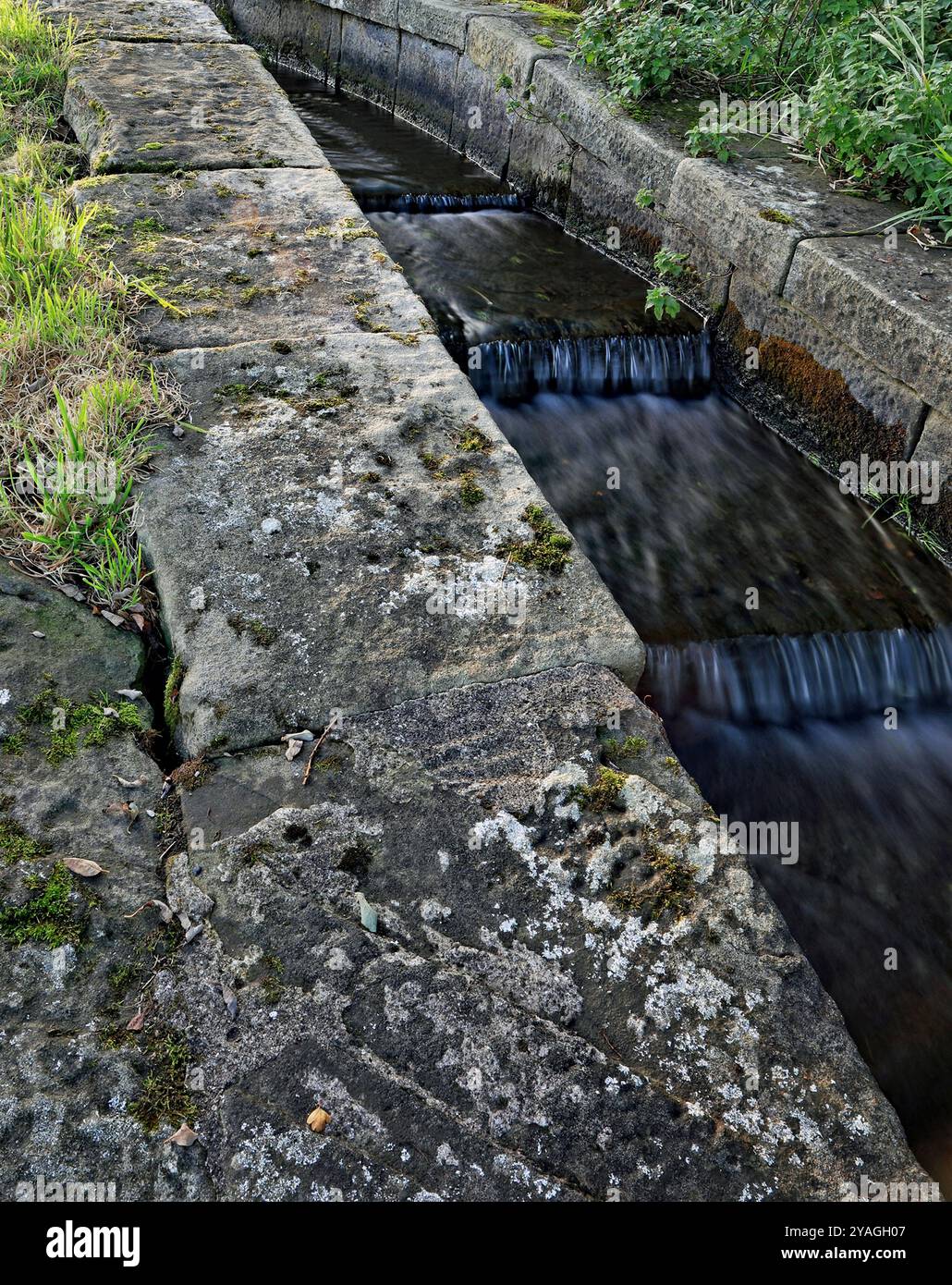 Das überschüssige Wasser aus dem Kanal über Schleuse vier des Rufford-Arms des Leeds- und Liverpool-Kanals fließt um die Schleuse im Stein-Nebenwasserkanal. Stockfoto