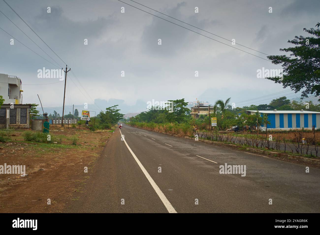Monsunwolken hängen über einem Abschnitt einer Staatsstraße, die durch Trimbakeshwar in Maharashtra bei Nashik verläuft. Stockfoto