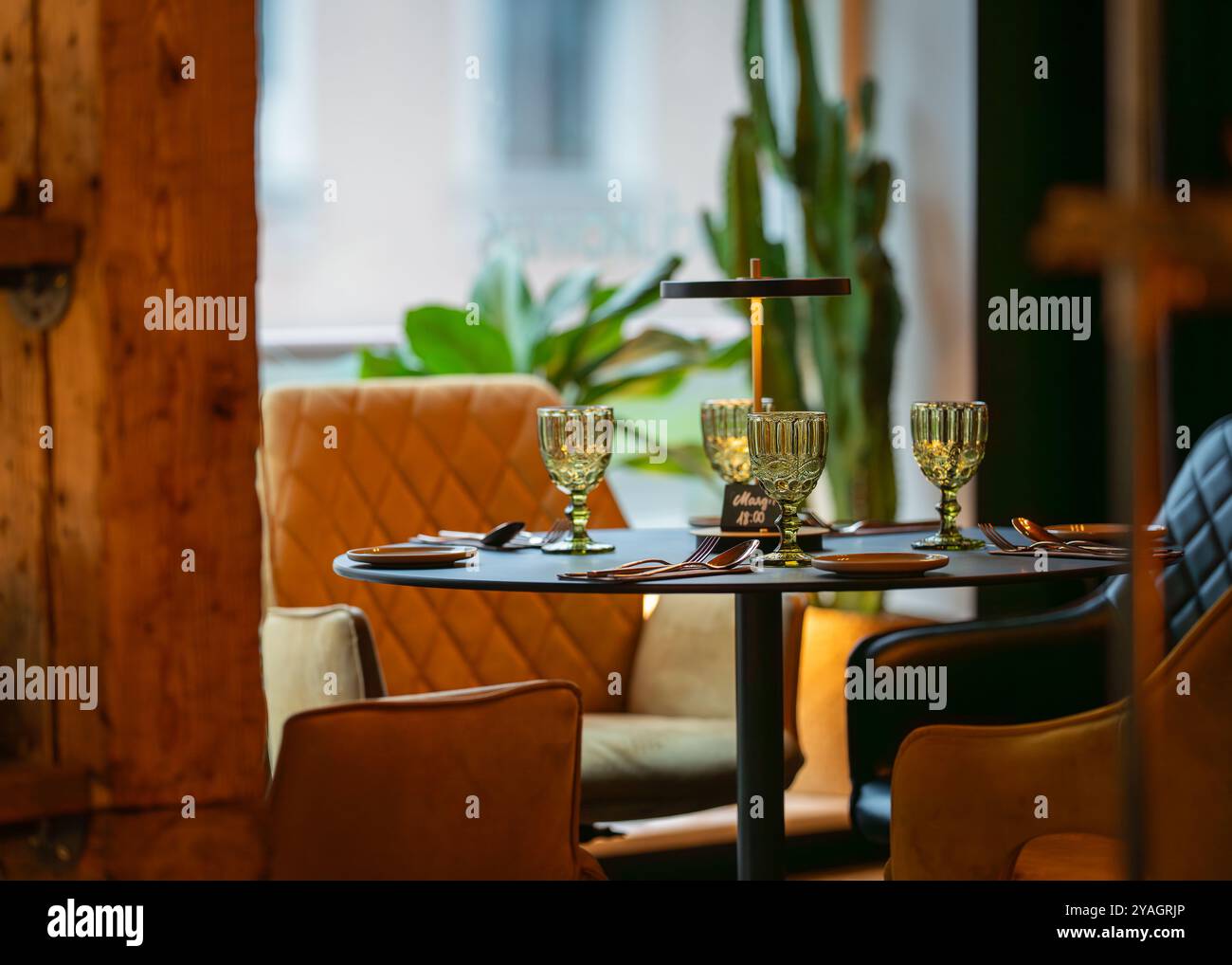 Ein runder, servierter Tisch steht für Gäste bereit. Runder Tisch mit leerem Teller, Gläsern, Gabeln, Serviette. Eleganter Esstisch. Stockfoto