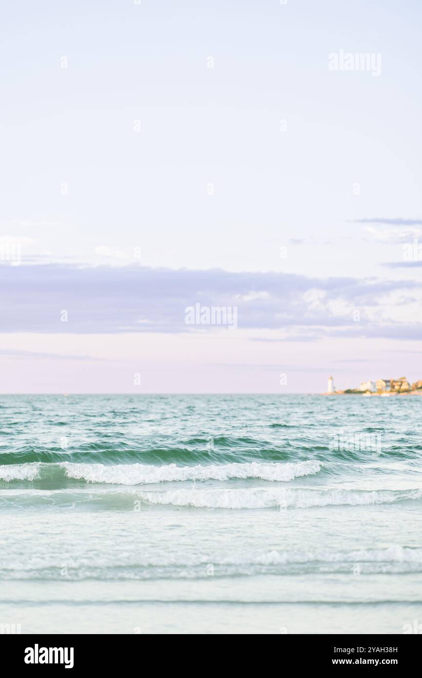 Sanfte Wellen entlang des Wingaersheek Beach mit einem entfernten Leuchtturm. Stockfoto