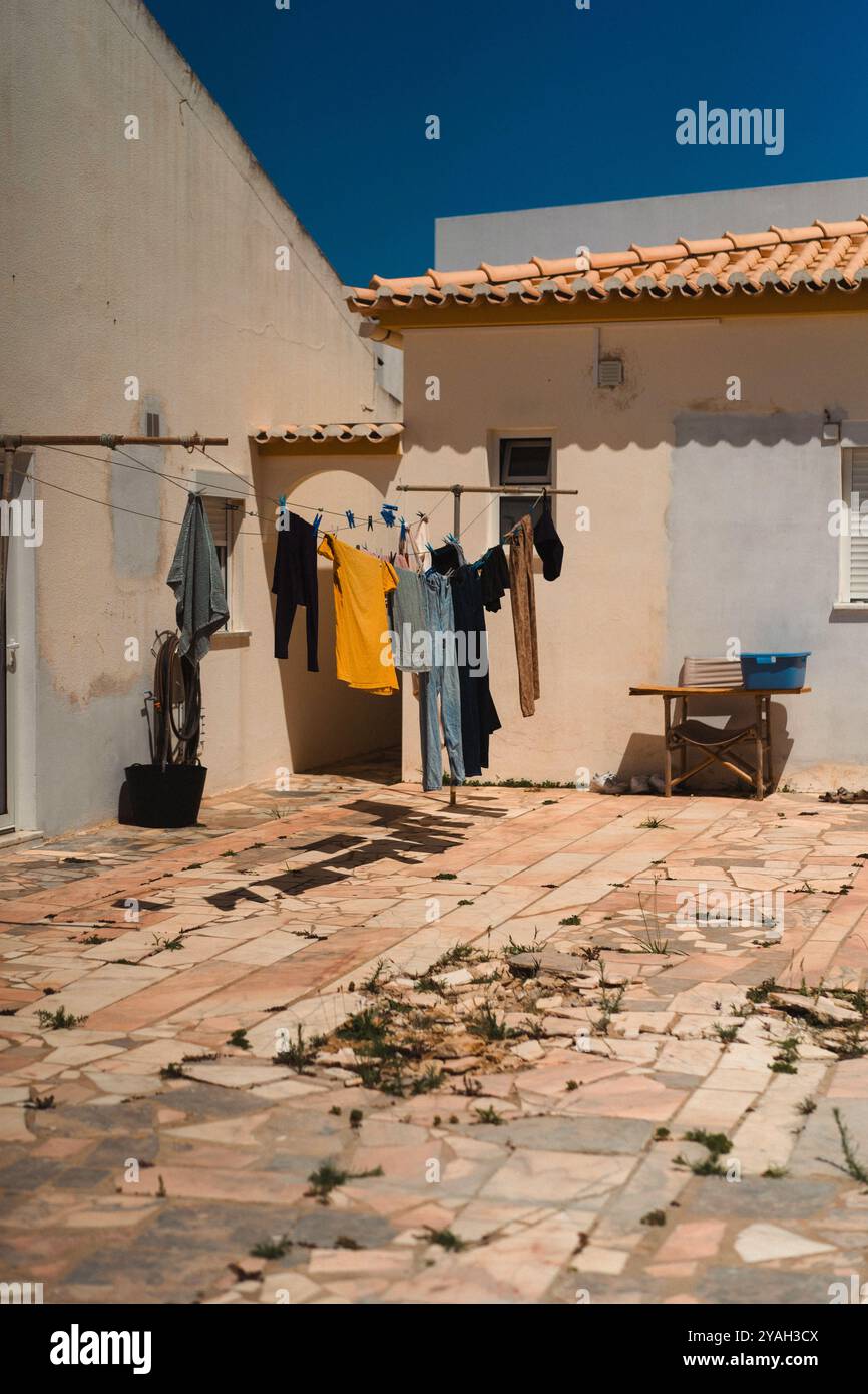 Bunte Kleidung, die draußen an einer Schnur im Hof trocknet. Stockfoto