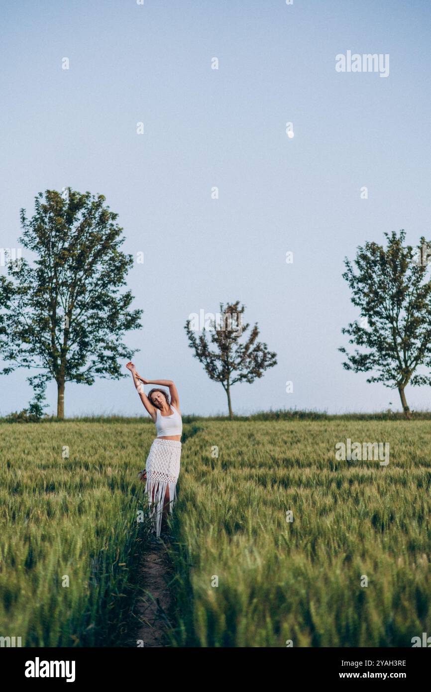 Junge Frau träumt auf einem grünen Feld an einem Sommerabend Stockfoto