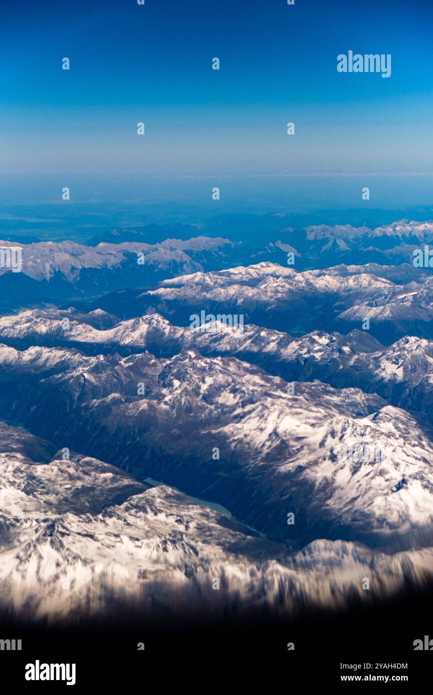 Blick von einem Jet-Flugzeug, während es über die Alpen mit tiefblauem Himmel fliegt. Stockfoto