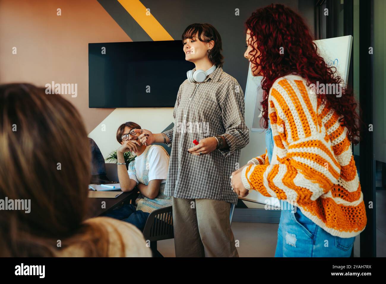 Generation Z-Profis nehmen eine Gruppenaufgabe mit einer Präsentation wahr und betonen Teamarbeit und Kommunikation in einer modernen Büroumgebung. Stockfoto